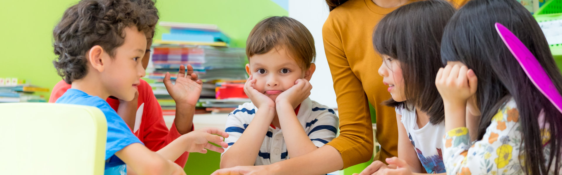 female teacher teaching kids reading book in classroom